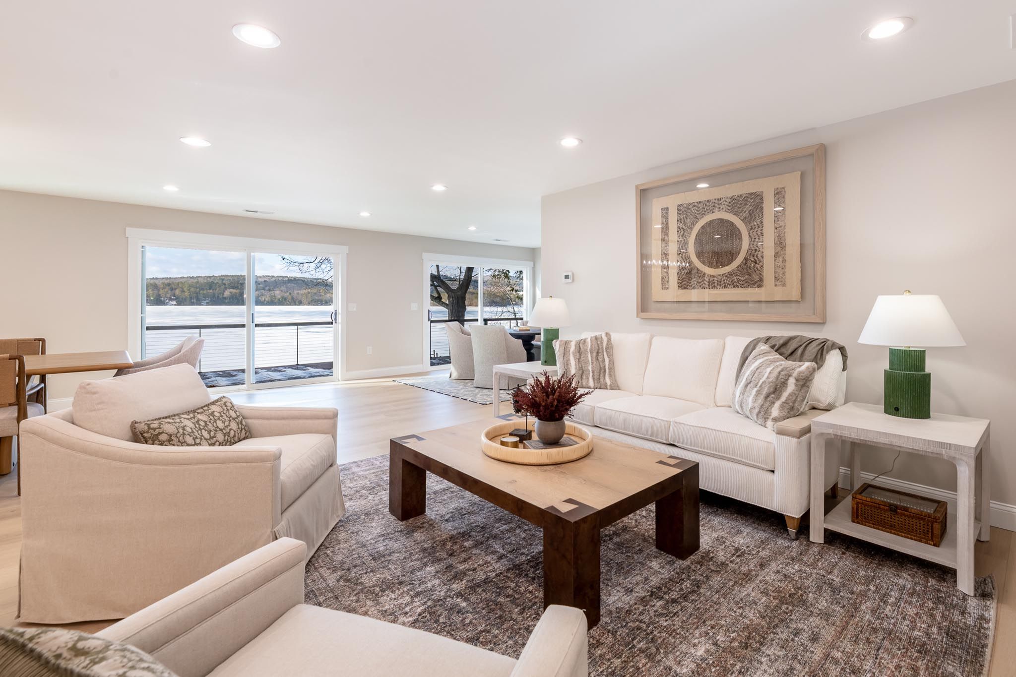 Waterside house with a dock and boat lift surrounded by lush trees at dusk.