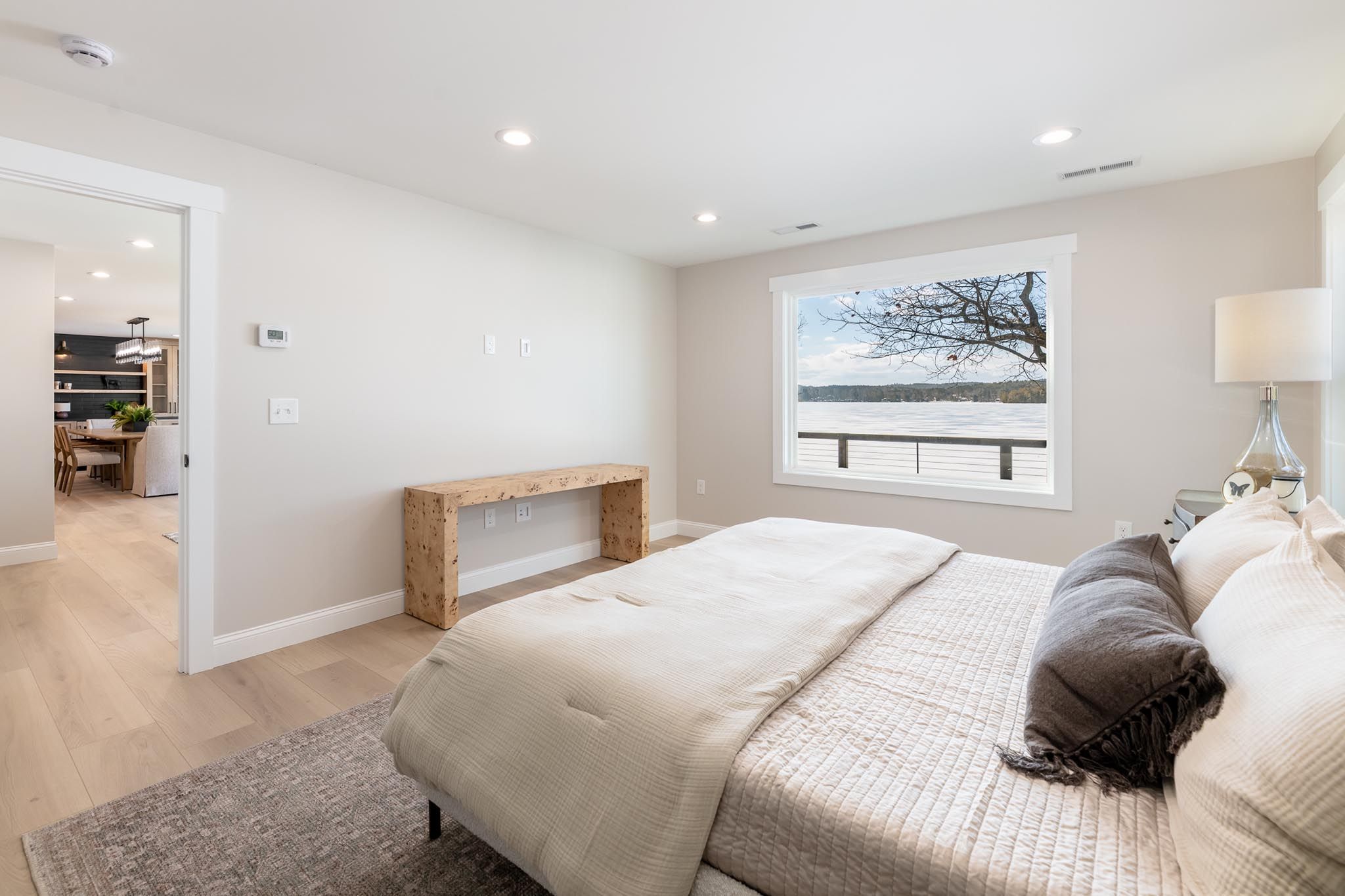 A motorboat speeding across a lake near a wooded shoreline with houses and docks, under a partly cloudy sky.