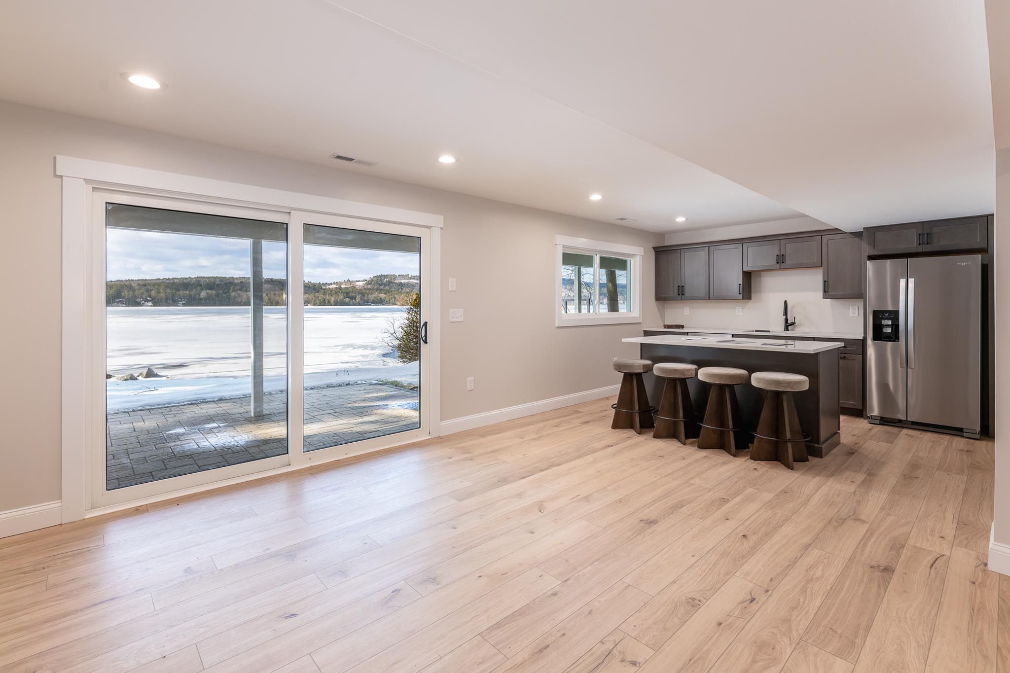 Scenic aerial view of a lakeside landscape featuring lush green forests, boats on the water, and residential homes surrounded by trees.