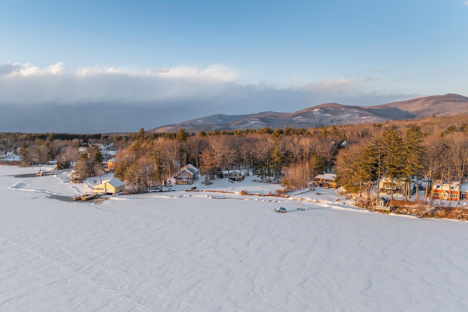 Person relaxing on a hammock by a lakeside reading a book on a sunny day