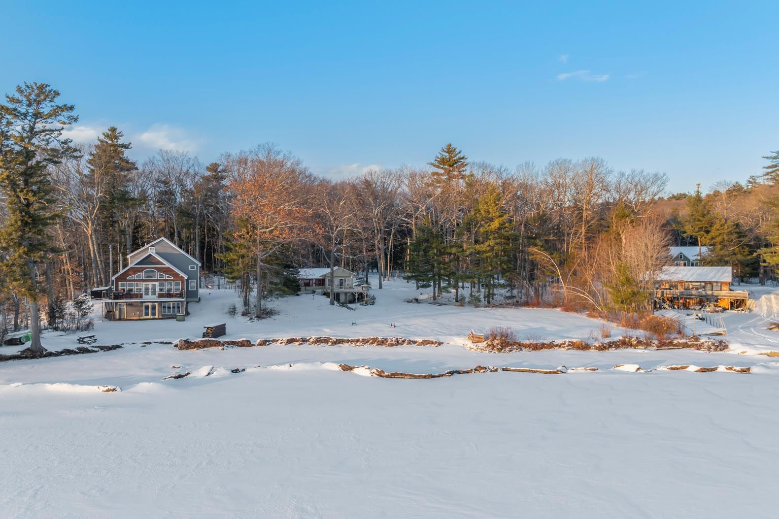 People enjoying water activities on a lake, with houses and lush greenery in the background.