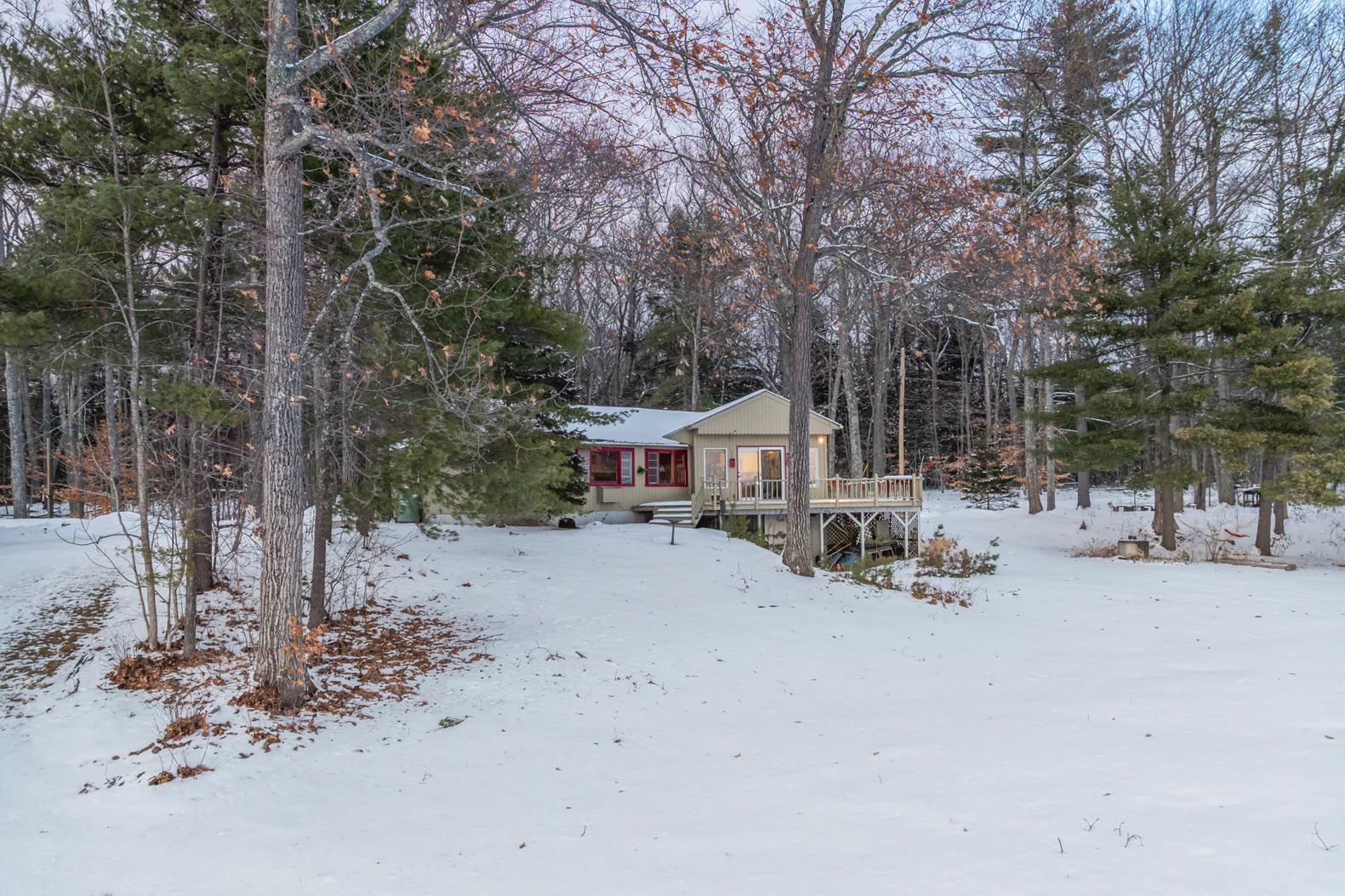 Scenic view of a grassy lakeside area with trees in the foreground and boats docked on the calm water under a clear blue sky.