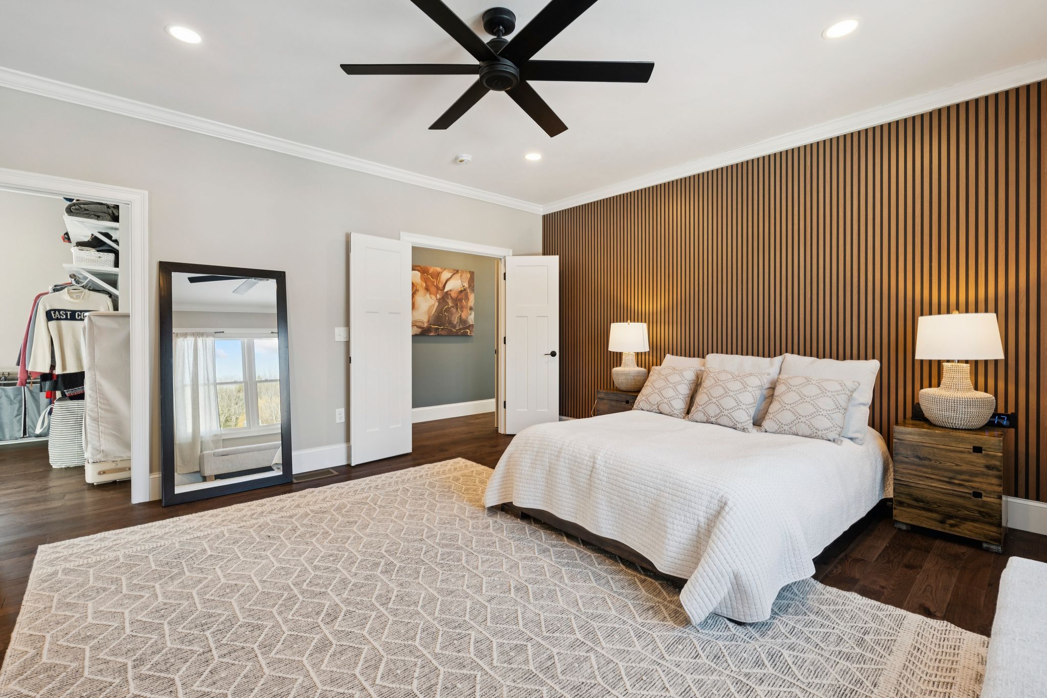 Modern blue house with stone accents, large windows, and a three-car garage, surrounded by snow and leafless trees in winter.