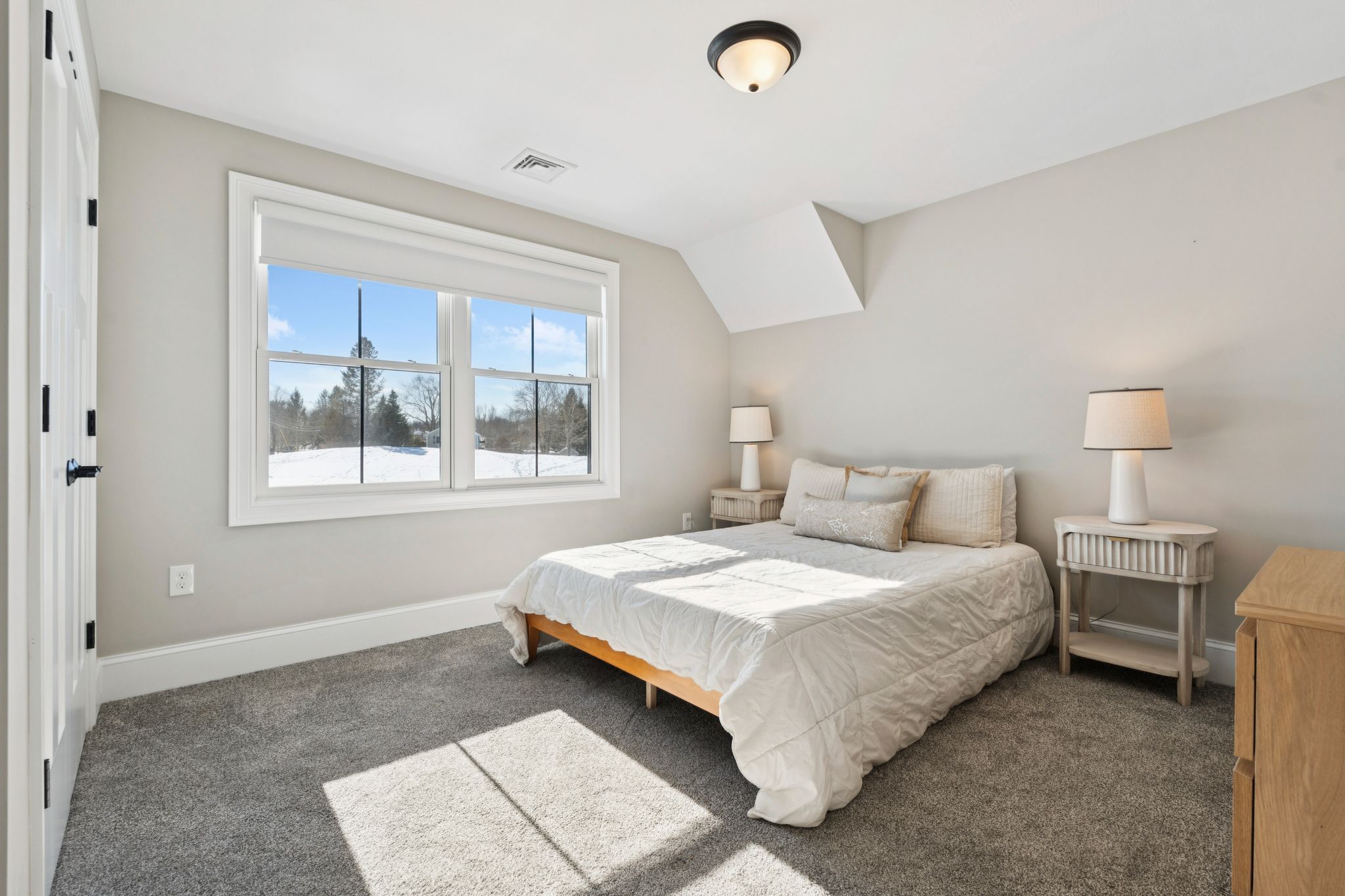 Snow-covered backyard with leafless trees and a clear blue sky during winter day