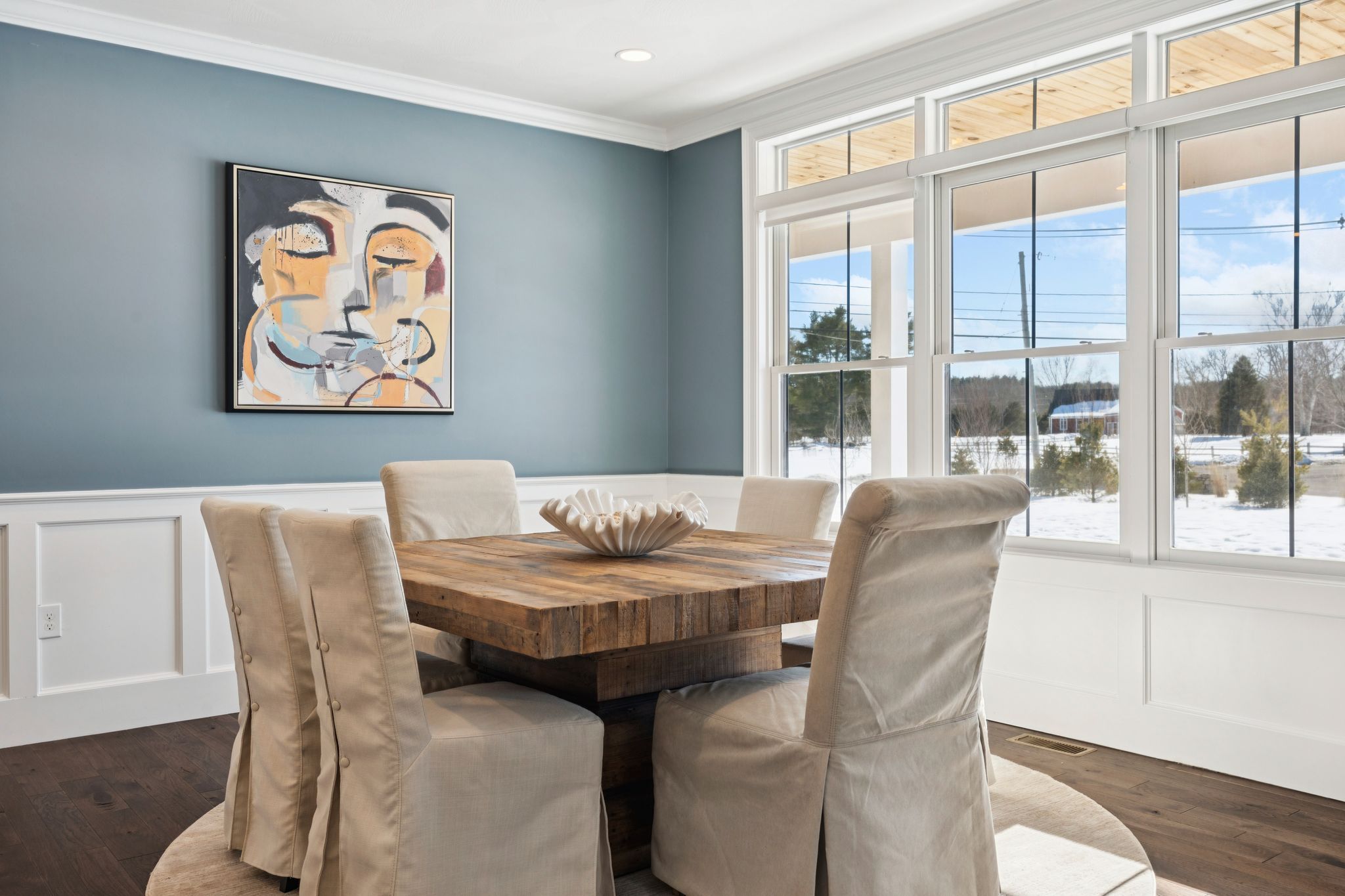 Snow-covered backyard with leafless trees and a clear blue sky during winter day