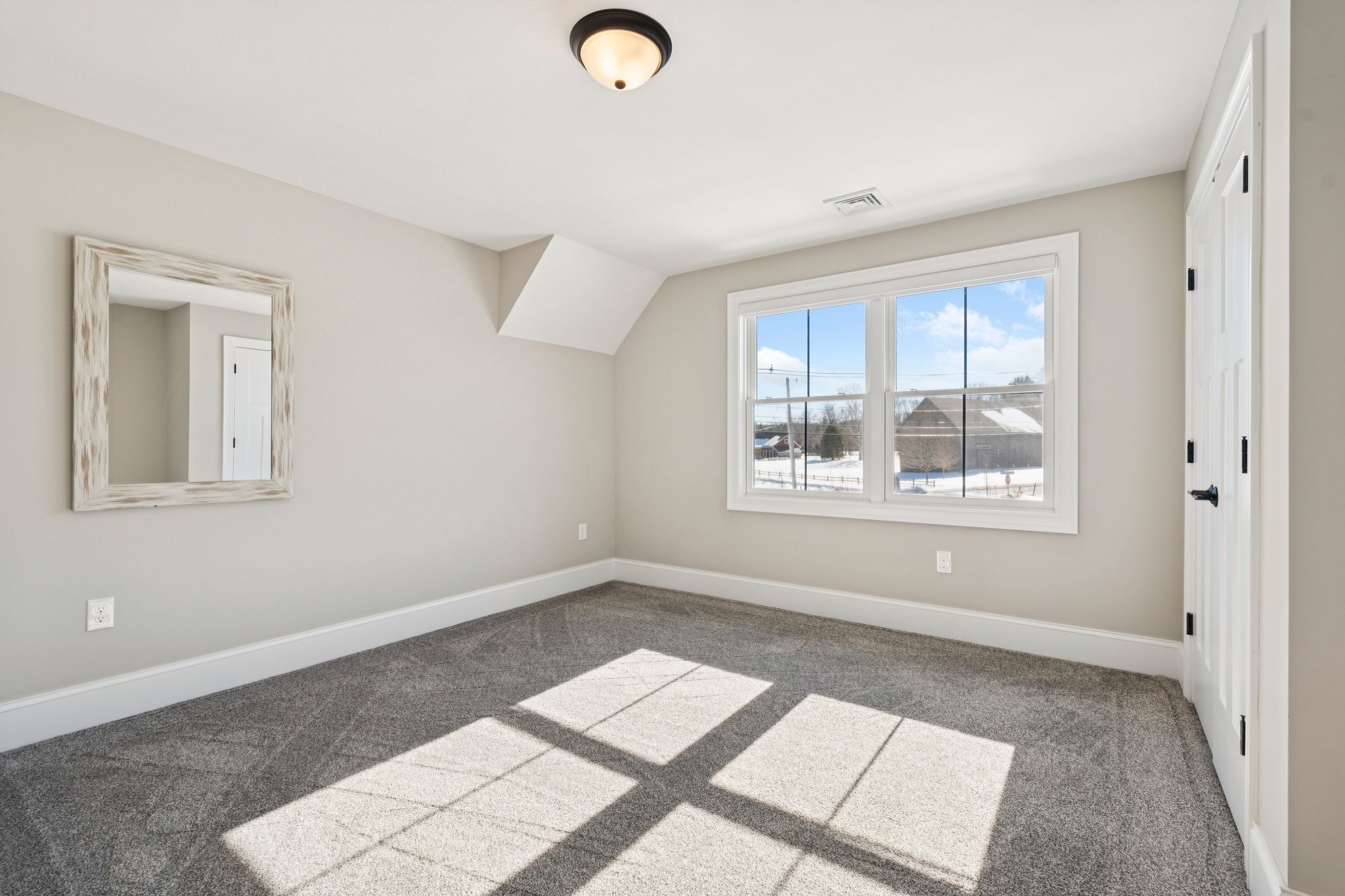 Snow-covered backyard with leafless trees and a clear blue sky during winter day
