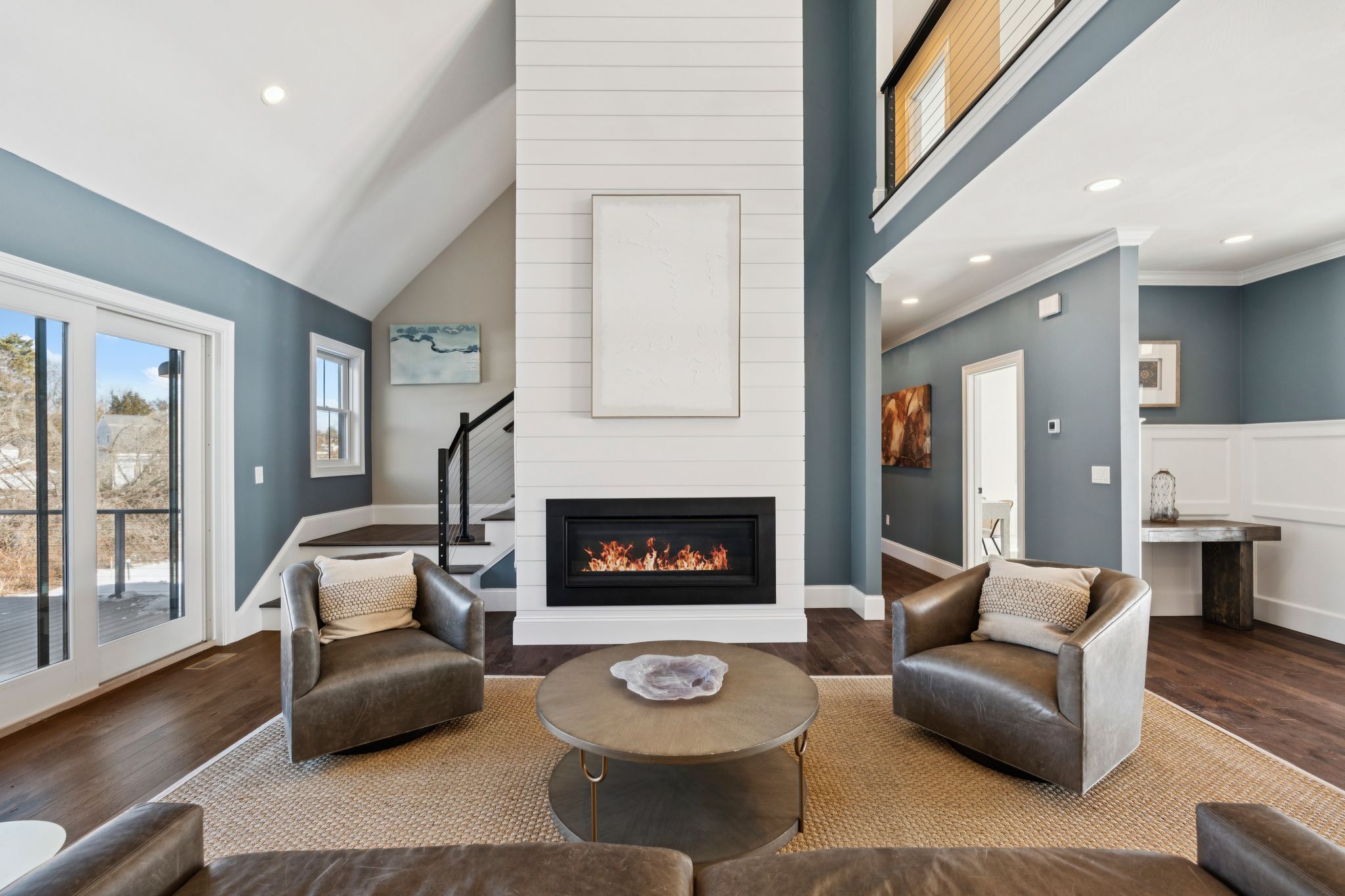 Modern black house with a stone foundation and snow-covered landscape during sunset