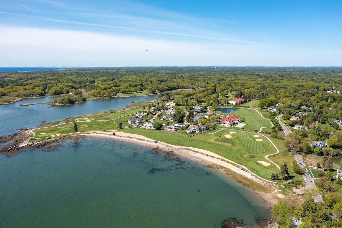 Close-up of a golf tee, golf ball, and iron golf club on a lush green golf course during sunset.