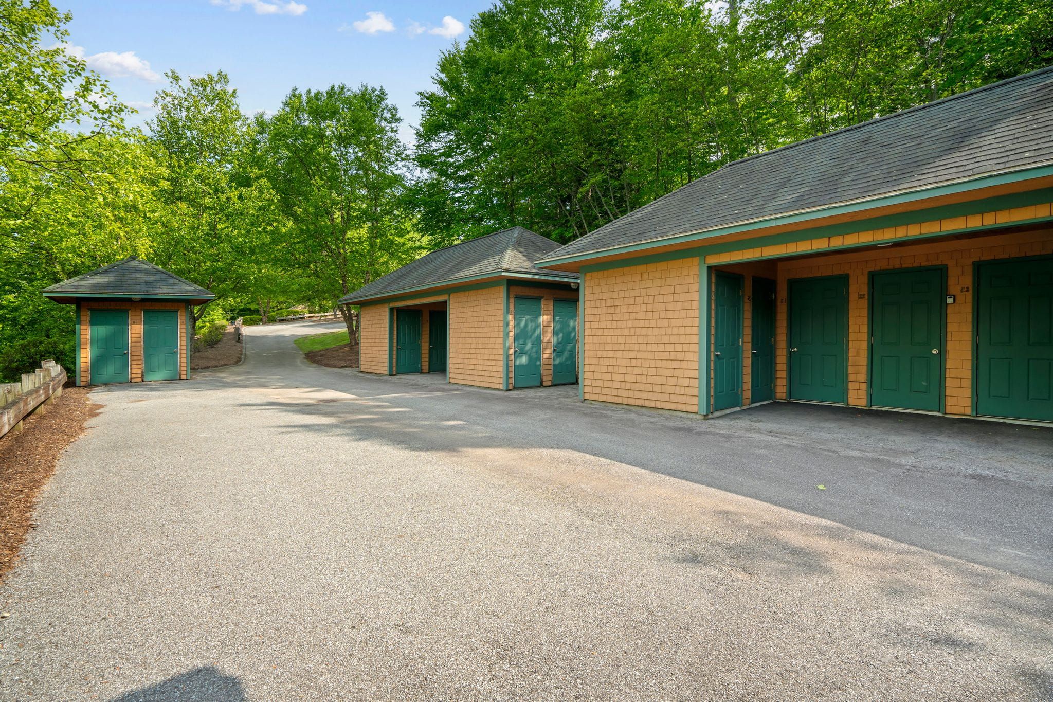 Interior view of a modern home with a built-in wooden bench with blue pillows, a wooden cabinet, framed artwork, and a dining area with large windows showing greenery outside