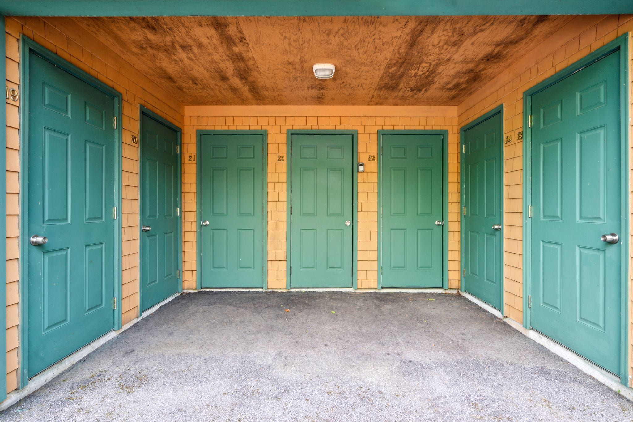 Bright and spacious bedroom with a four-poster bed, large windows with lush greenery view, flat-screen TV, and cozy seating area, featuring a neutral color palette and modern decor.