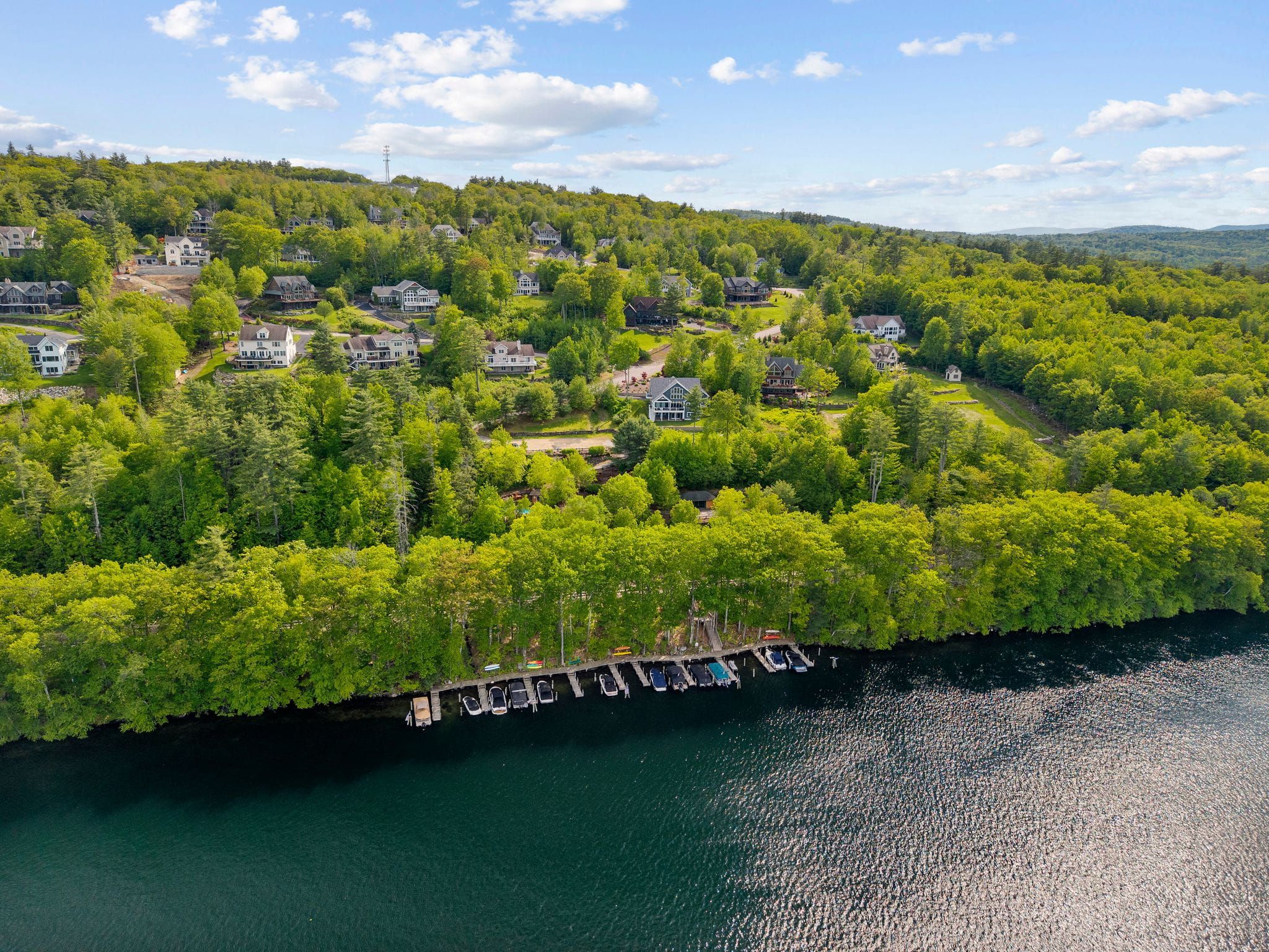 Modern kitchen with granite countertops, grey cabinetry, mosaic backsplash, stainless steel appliances, and a breakfast bar with blue upholstered chairs, featuring a dining area with a vase of yellow flowers and ocean-themed artwork on the wall.