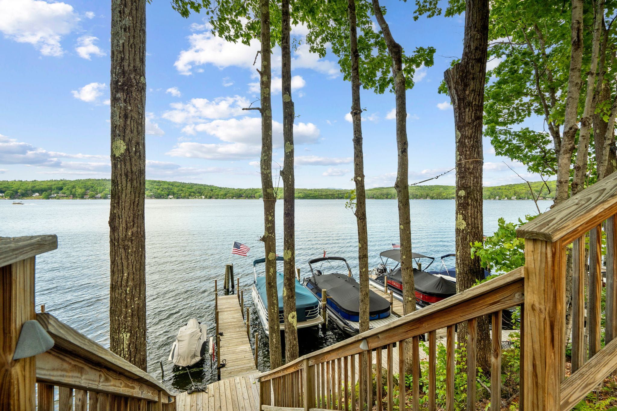 Modern kitchen with stainless steel appliances, wooden cabinetry, granite countertops, mosaic tile backsplash, and hardwood flooring in an open-concept living space