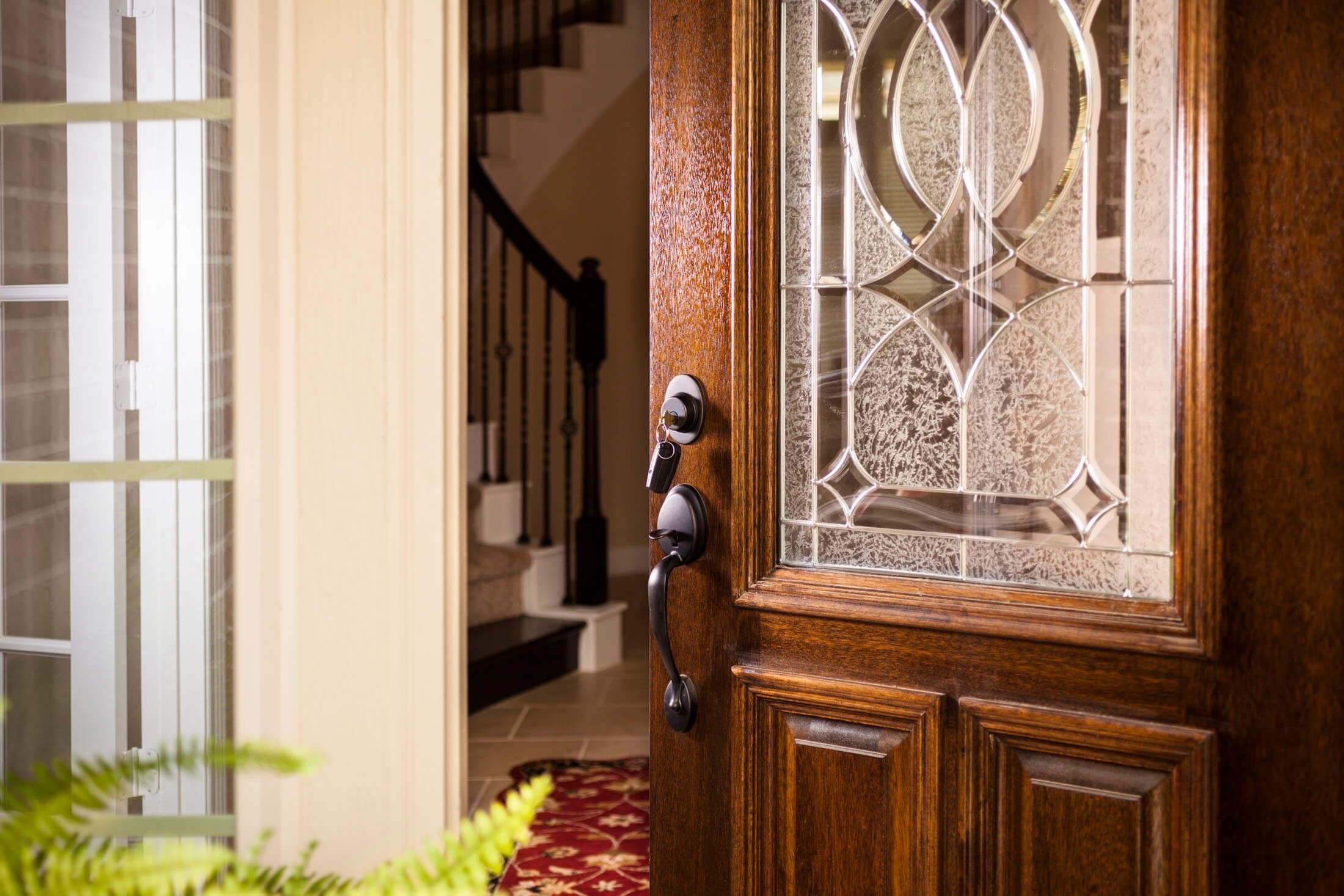 Close-up of a wood front door with decorative glass and brass hardware at 6915 Eagle Rd
