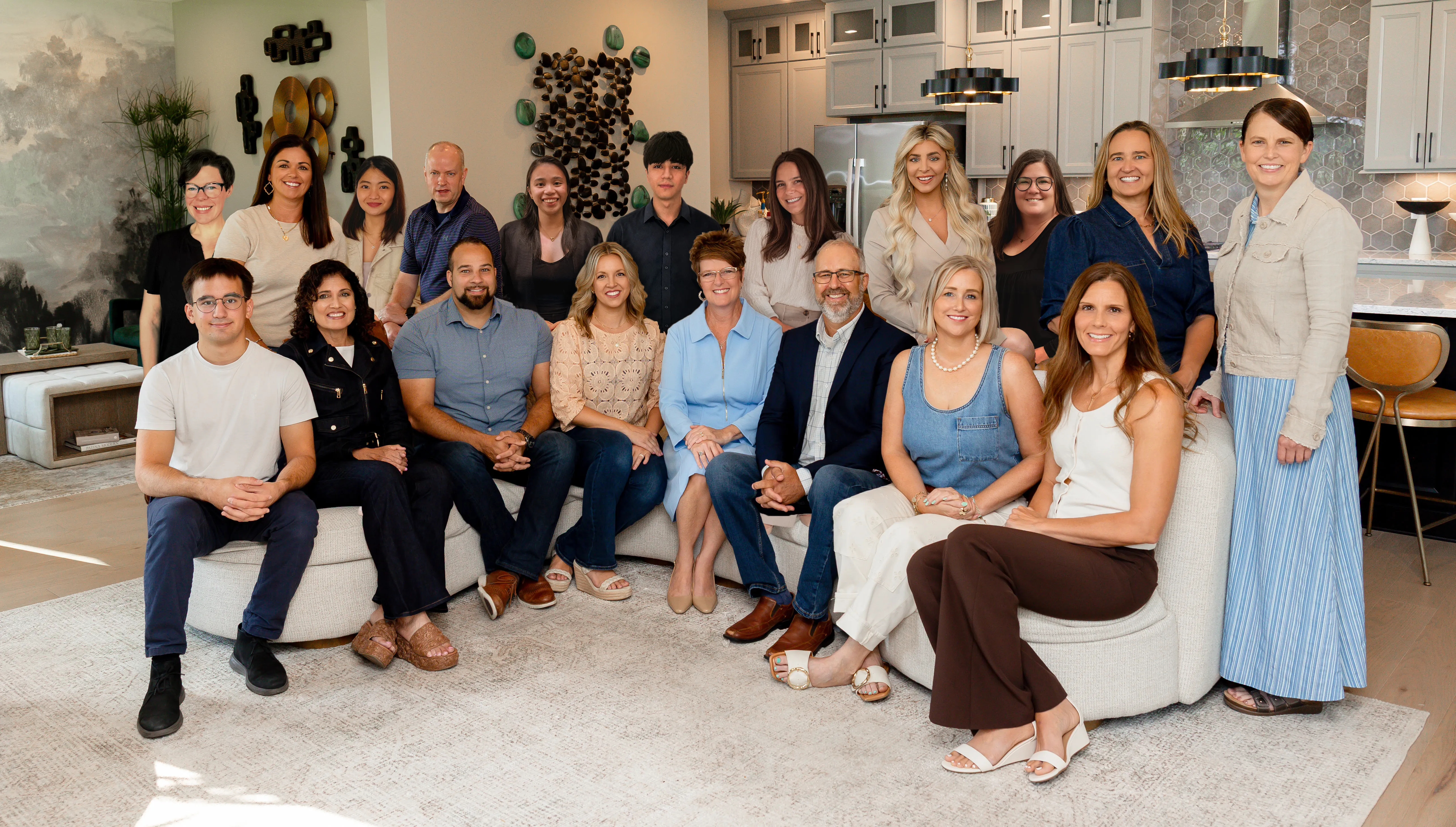 Group portrait of diverse professionals smiling in modern living room, representing team or business colleagues.