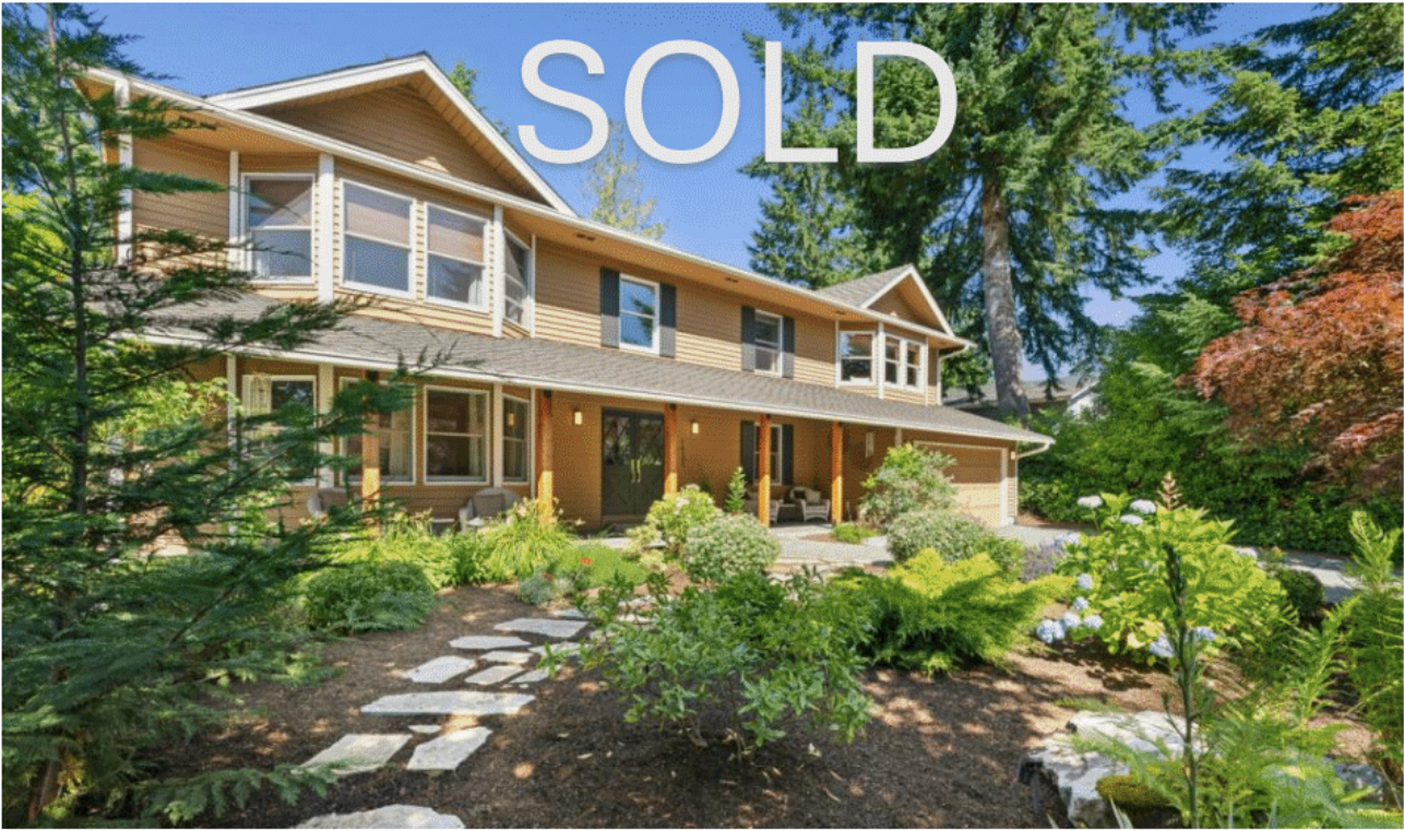 Beautiful two-story house with a well-maintained front yard featuring lush greenery and flower beds, sold property under blue sky.