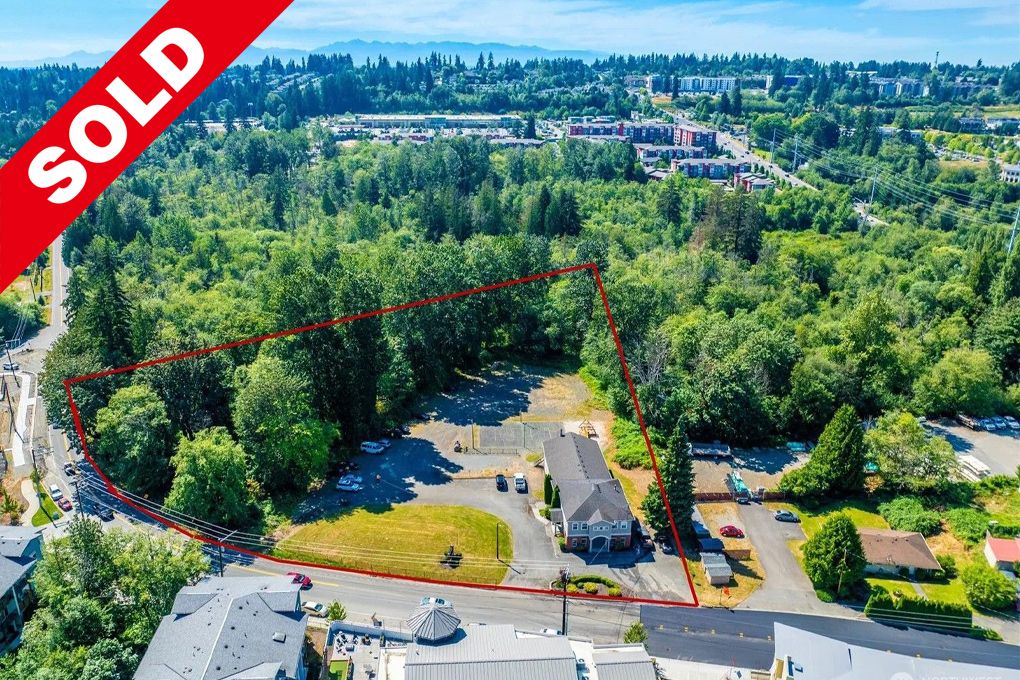 Aerial view of a cleared residential property with a house, surrounded by a wooded area, outlined in red, with a 