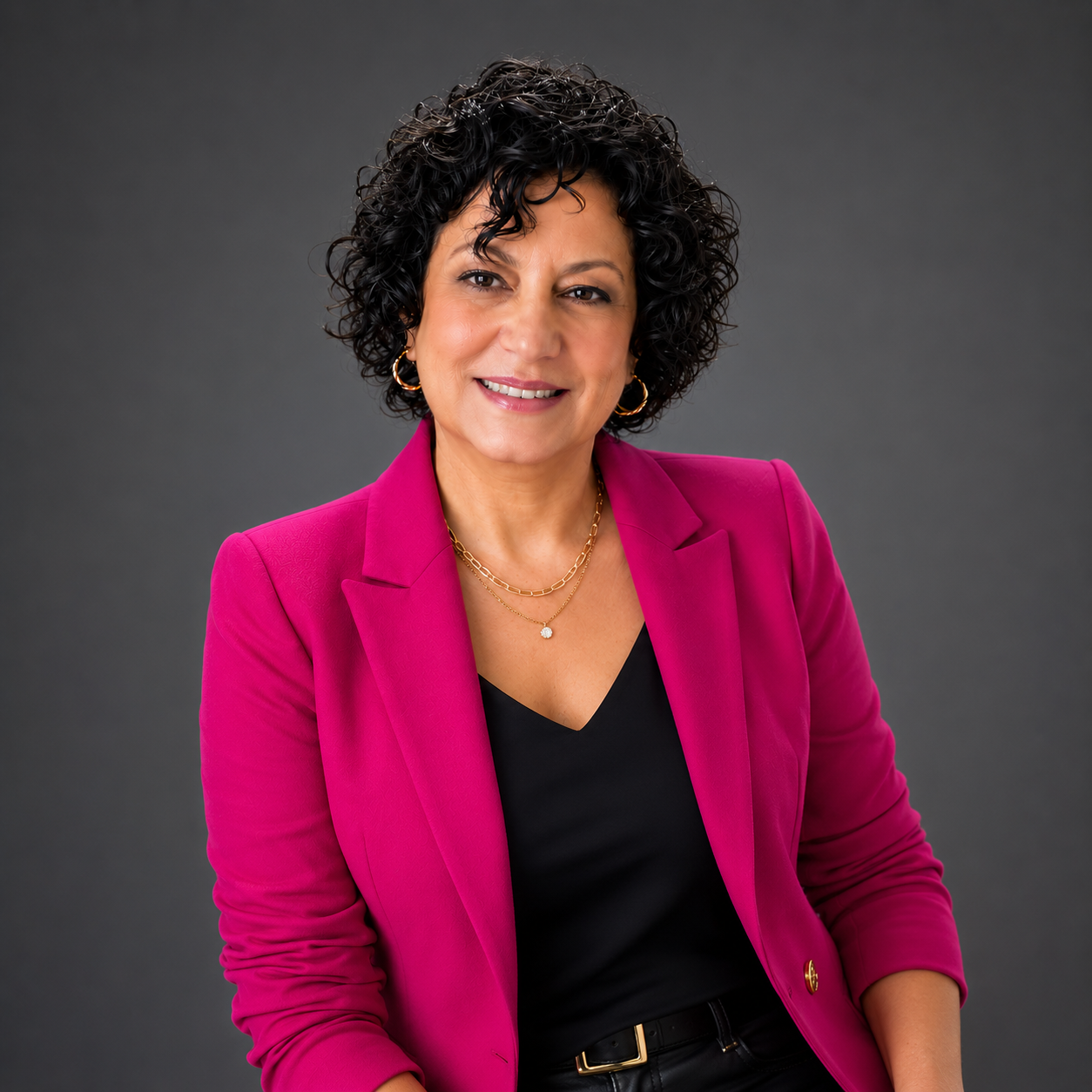 Black and white portrait of a woman with curly short hair, smiling gently, wearing earrings and a patterned top.