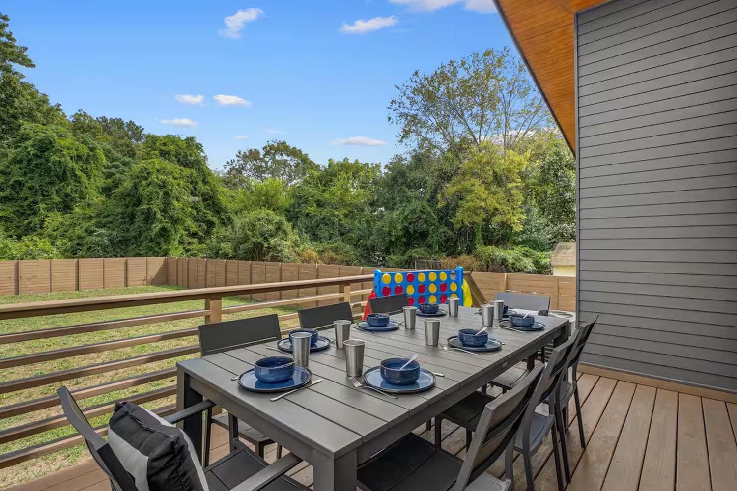 Bright and modern living room with beige sofas, colorful throw pillows, wooden coffee table, black and leather accent chairs, large window with orange curtains, hardwood floors, and decorative wall art.