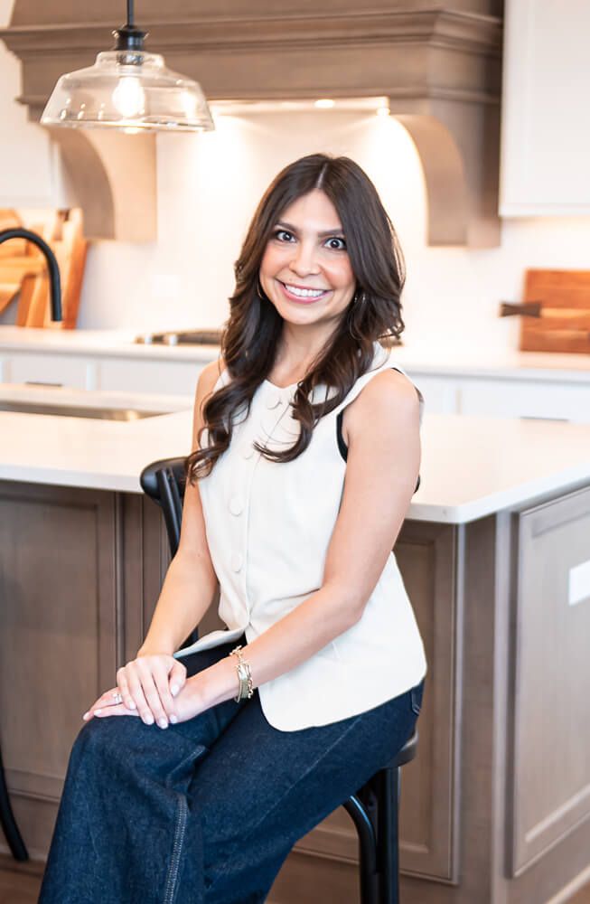 Portrait of a smiling young woman with braces, wearing a navy blazer and hoop earrings, in a professional indoor setting.