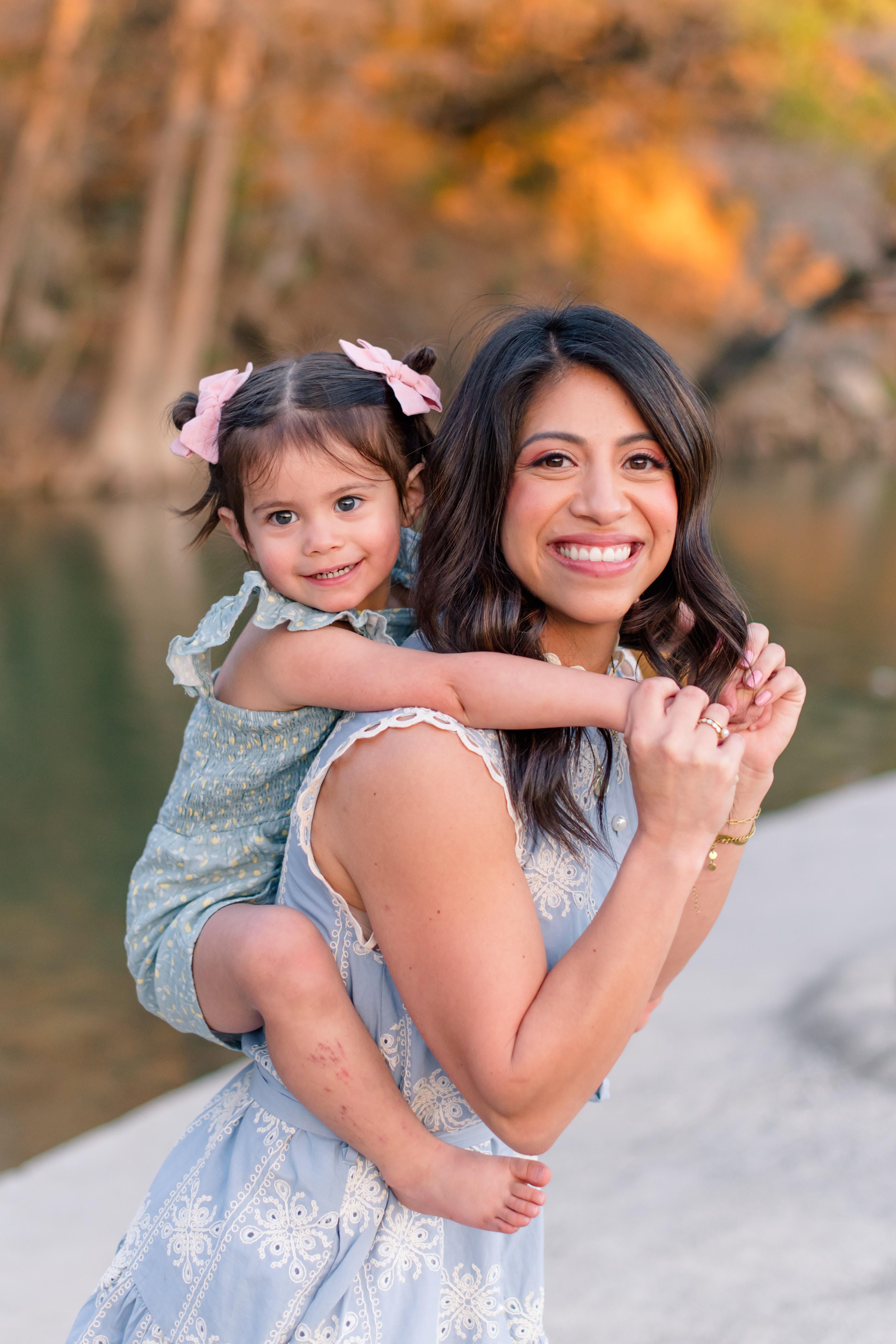 Portrait of a smiling woman in a white sleeveless dress, recognized as a top realtor at TKS, standing in a modern kitchen with a confident pose.