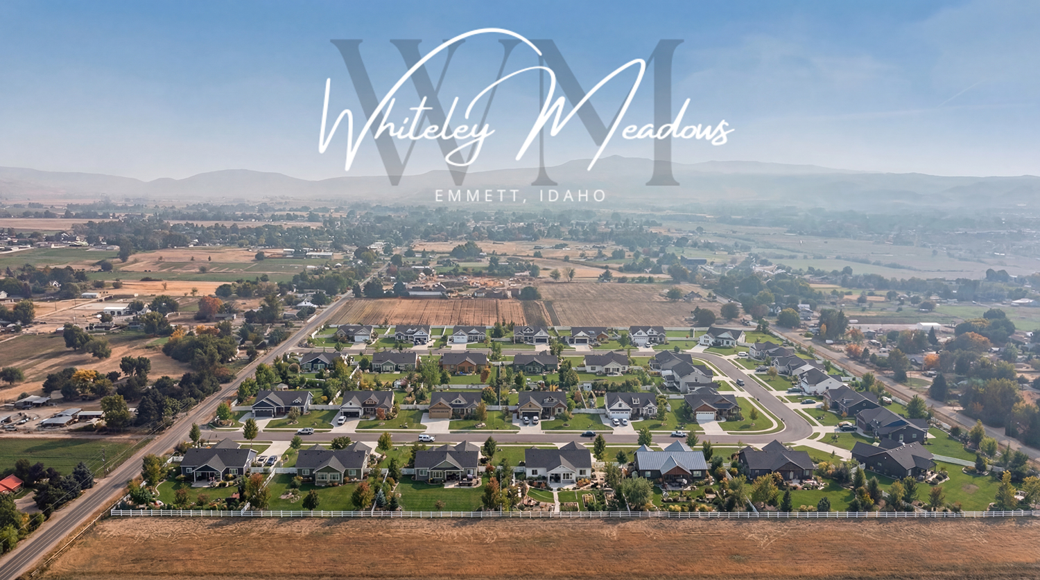 Aerial view of a large construction site with cleared land and road access, surrounded by residential and rural areas with hills in the background.