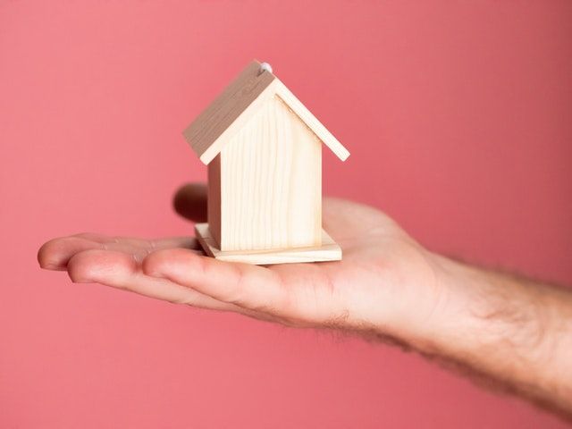 a small wooden house on a person's hand