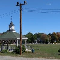 Small park with gazebo, utility pole, and open grassy area under a clear blue sky