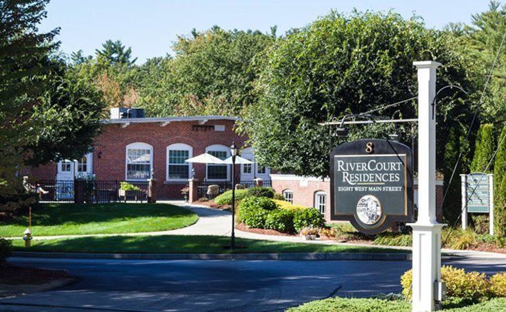 River Court Residences on West Main Street in a landscaped residential area with brick buildings, green lawns, and mature trees.