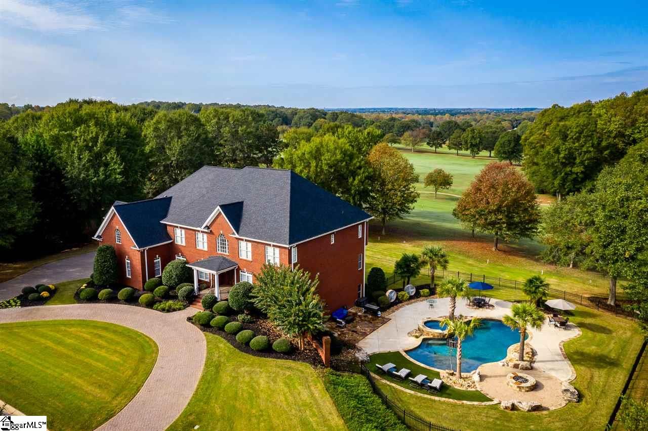 Sunset over a bridge crossing a body of water with boats docked at the piers, lush green marshland in the foreground, and a vibrant orange sky with scattered clouds.
