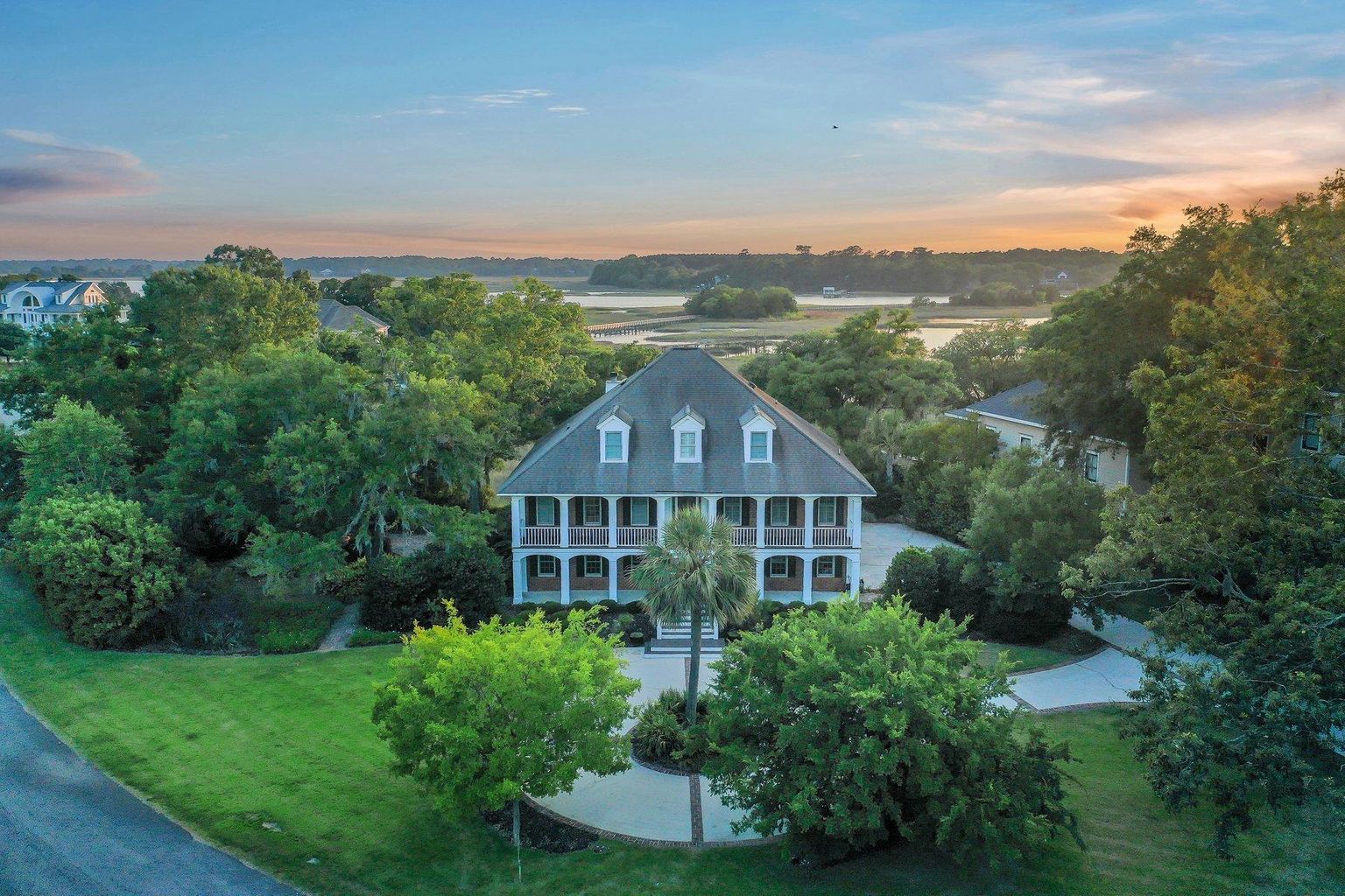 Scenic mountain trail during sunset with snow-capped peaks, lush green hillside, and vibrant sky.