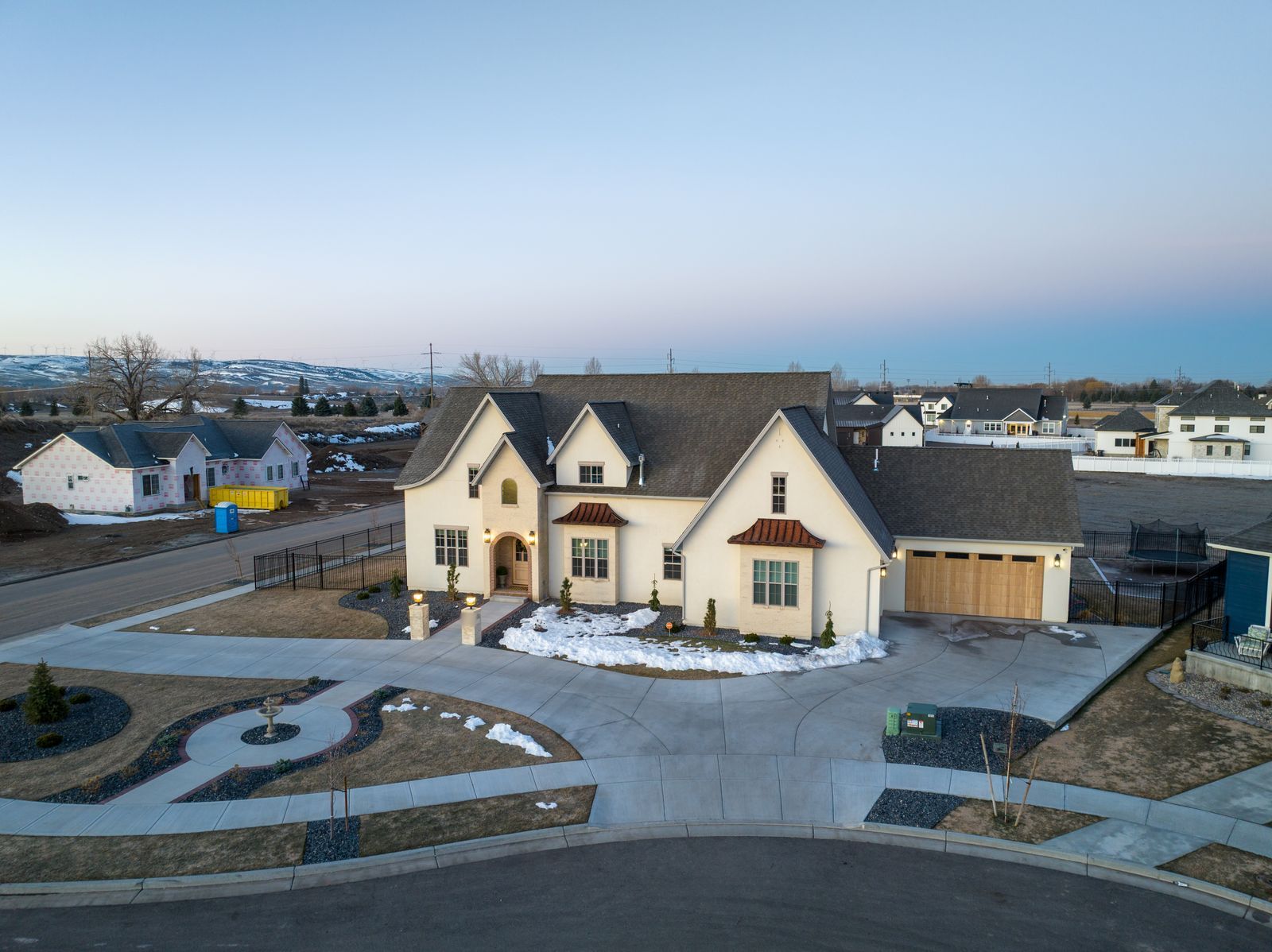 Aerial view of a cream two-story Hapco Construction custom home with a circular driveway in the Idaho Falls area