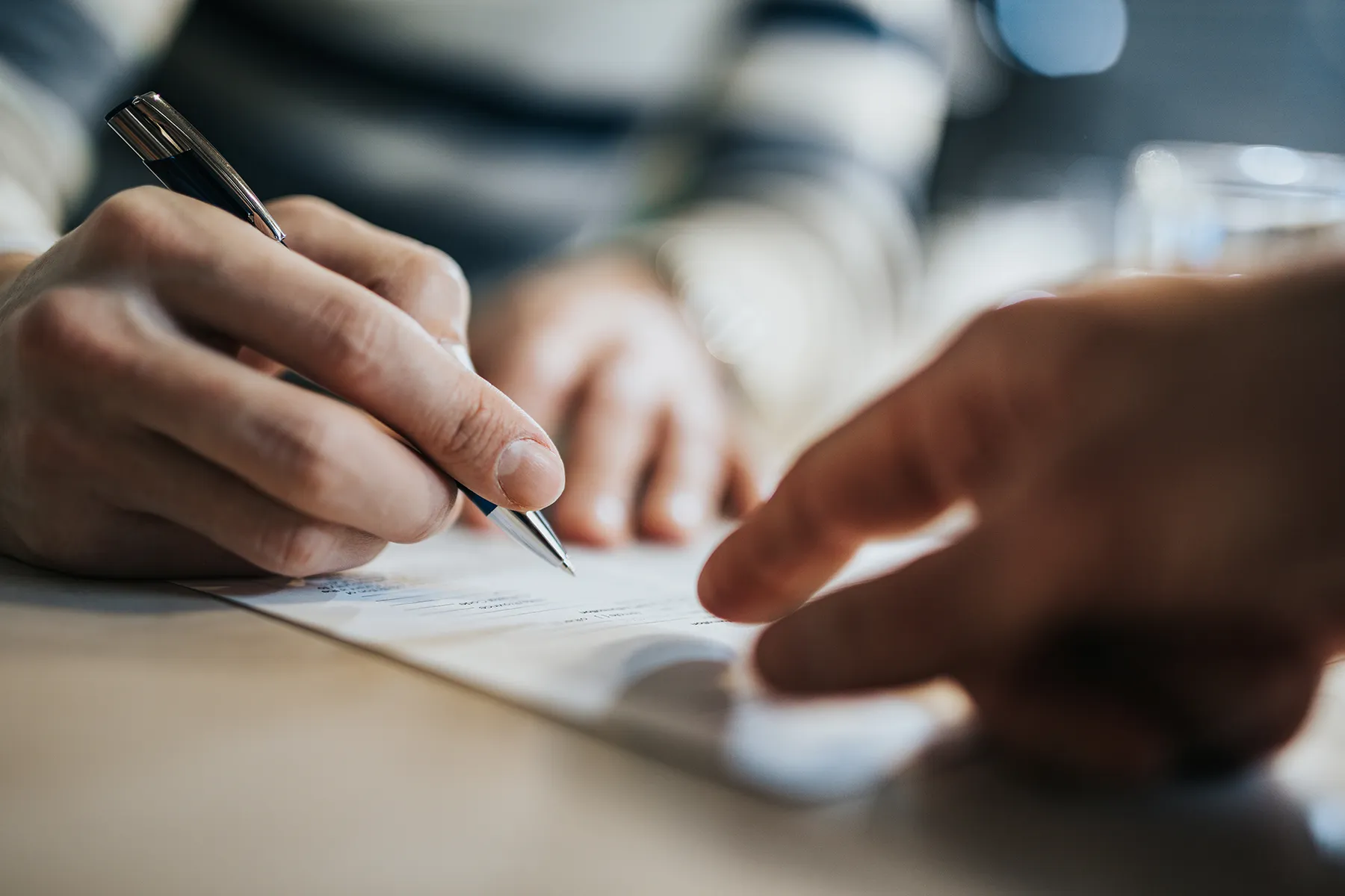 Person signing a document with a pen.